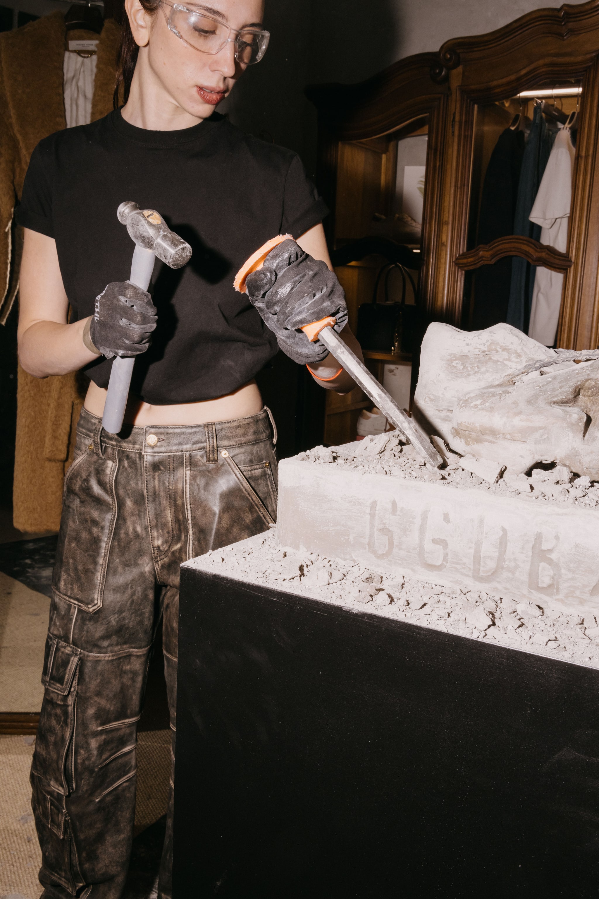 Close-up of artisan carving GGDB into stone using hammer and chisel during Haus Mexico city opening event