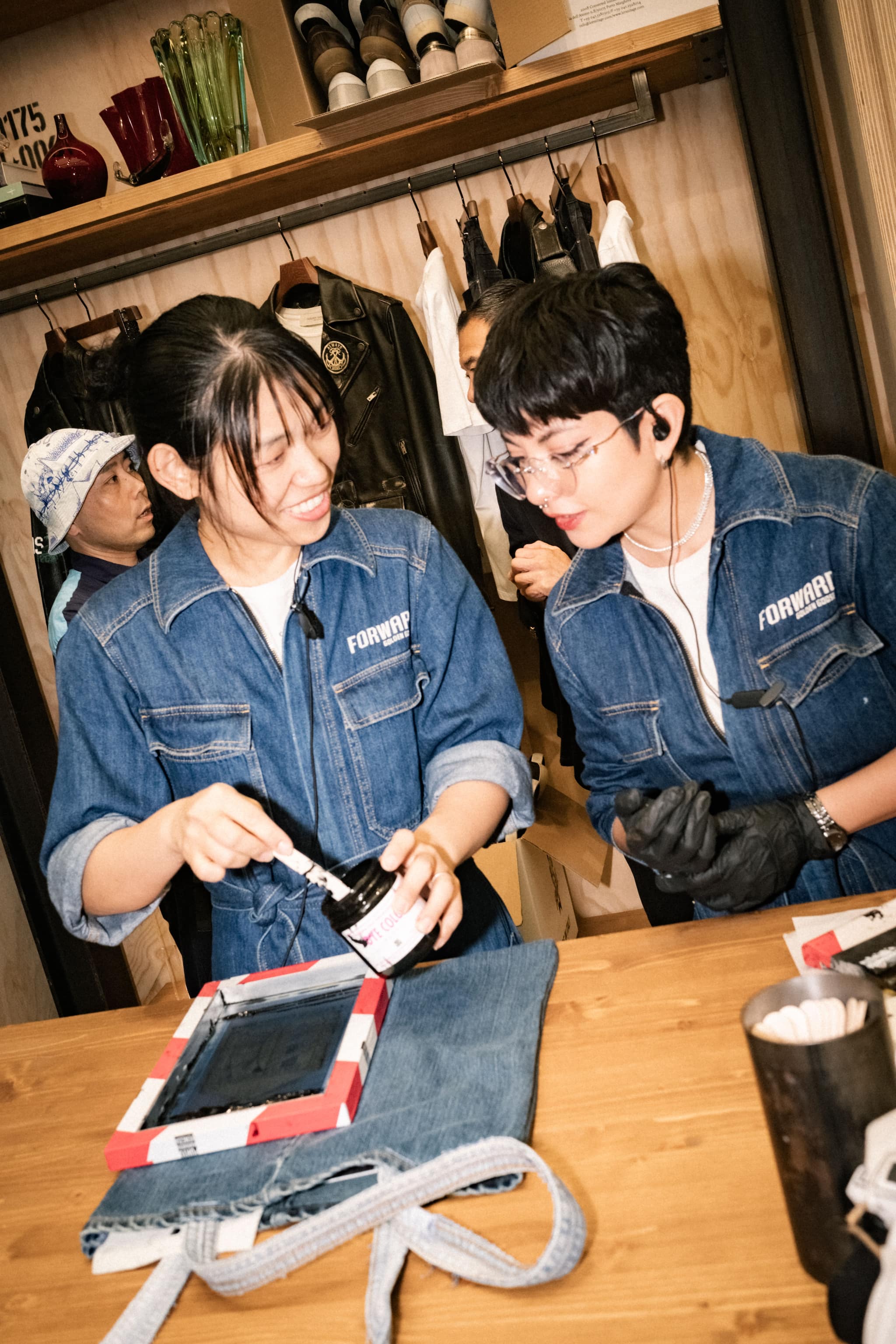 Two artisans showing ink for screen printing near denim garment at Tokyo Haus workshop event