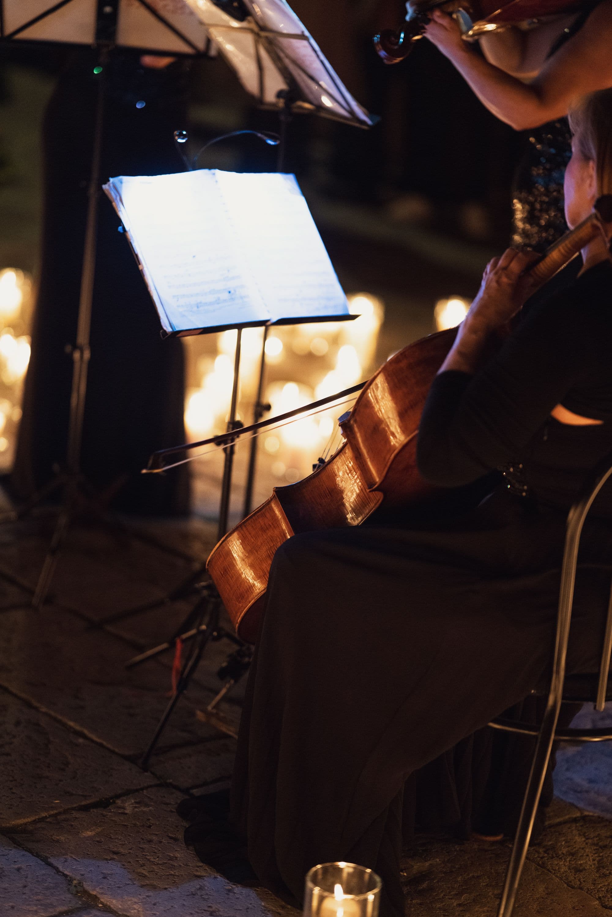 Cellist performing music surrounded by warm candlelight during Venice Haus event