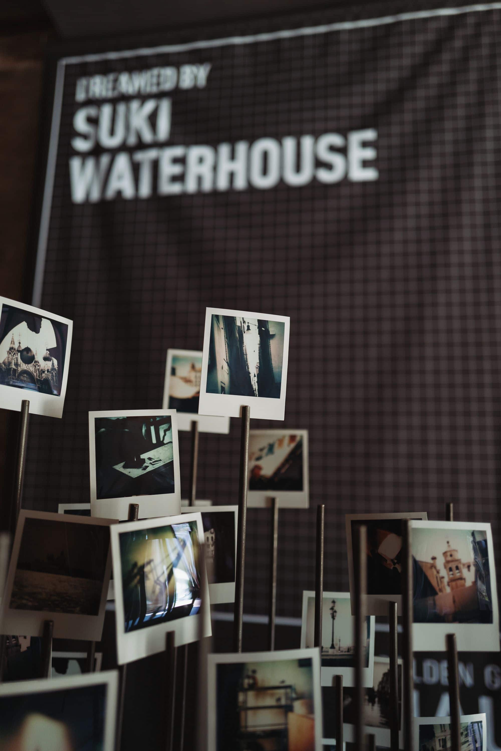 Polaroids displayed on metal stands near Suki Waterhouse sign at Venice Haus showcase