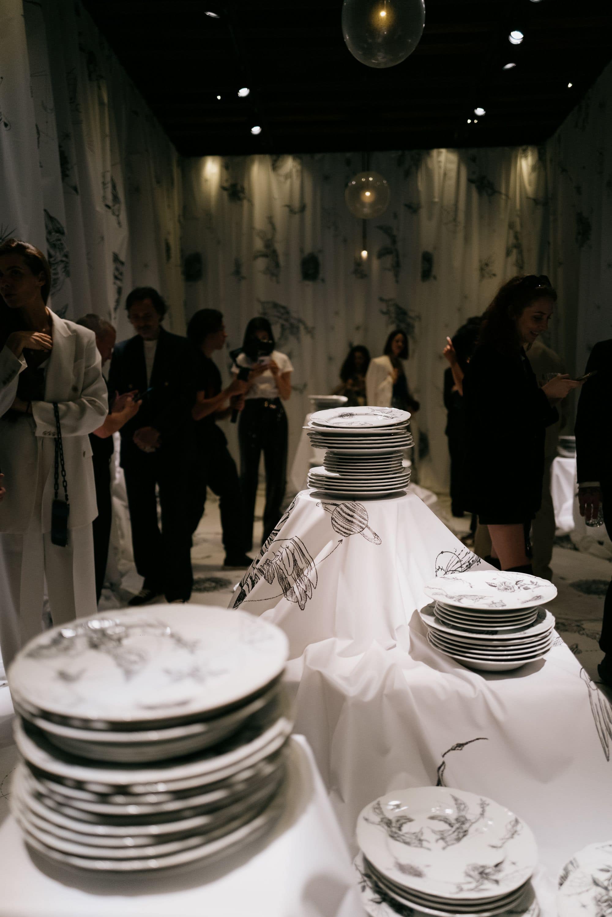 Table setting with illustrated plates in white draped gallery room during Venice Haus event