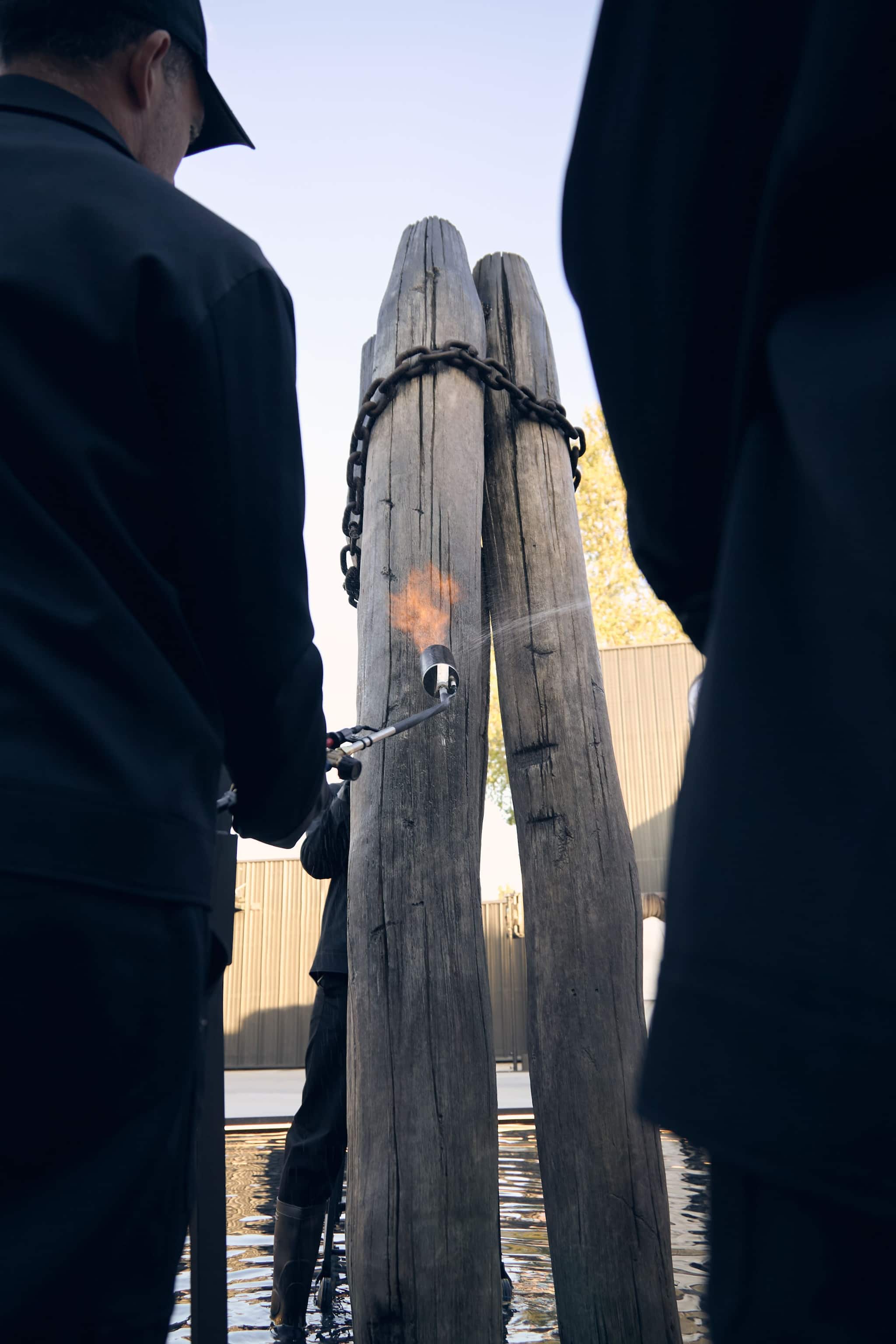 Artisans burning traditional wooden mooring poles with blowtorch during Venice Haus event