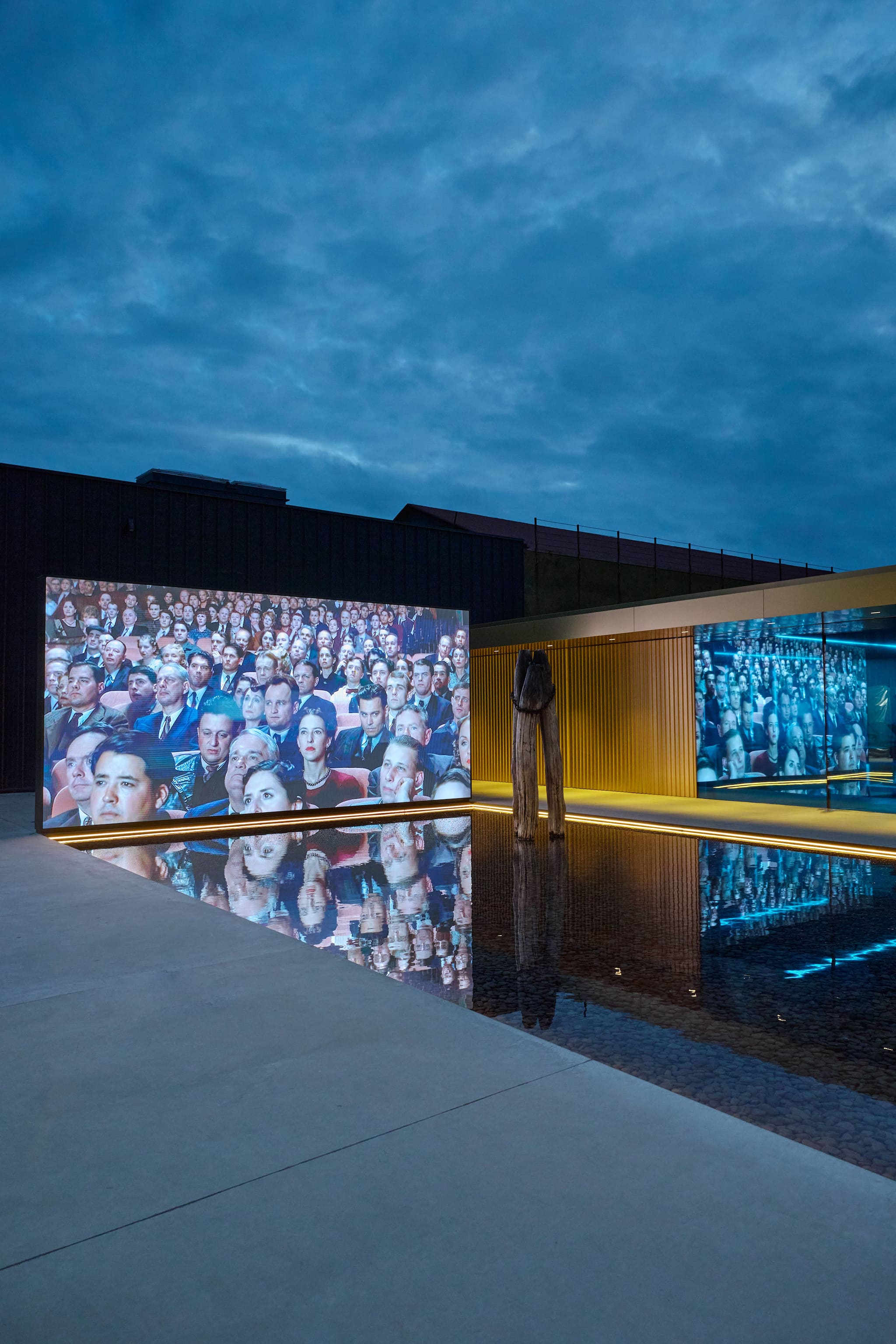Large screen showing vintage cinema audience reflecting on pool during Venice Haus event