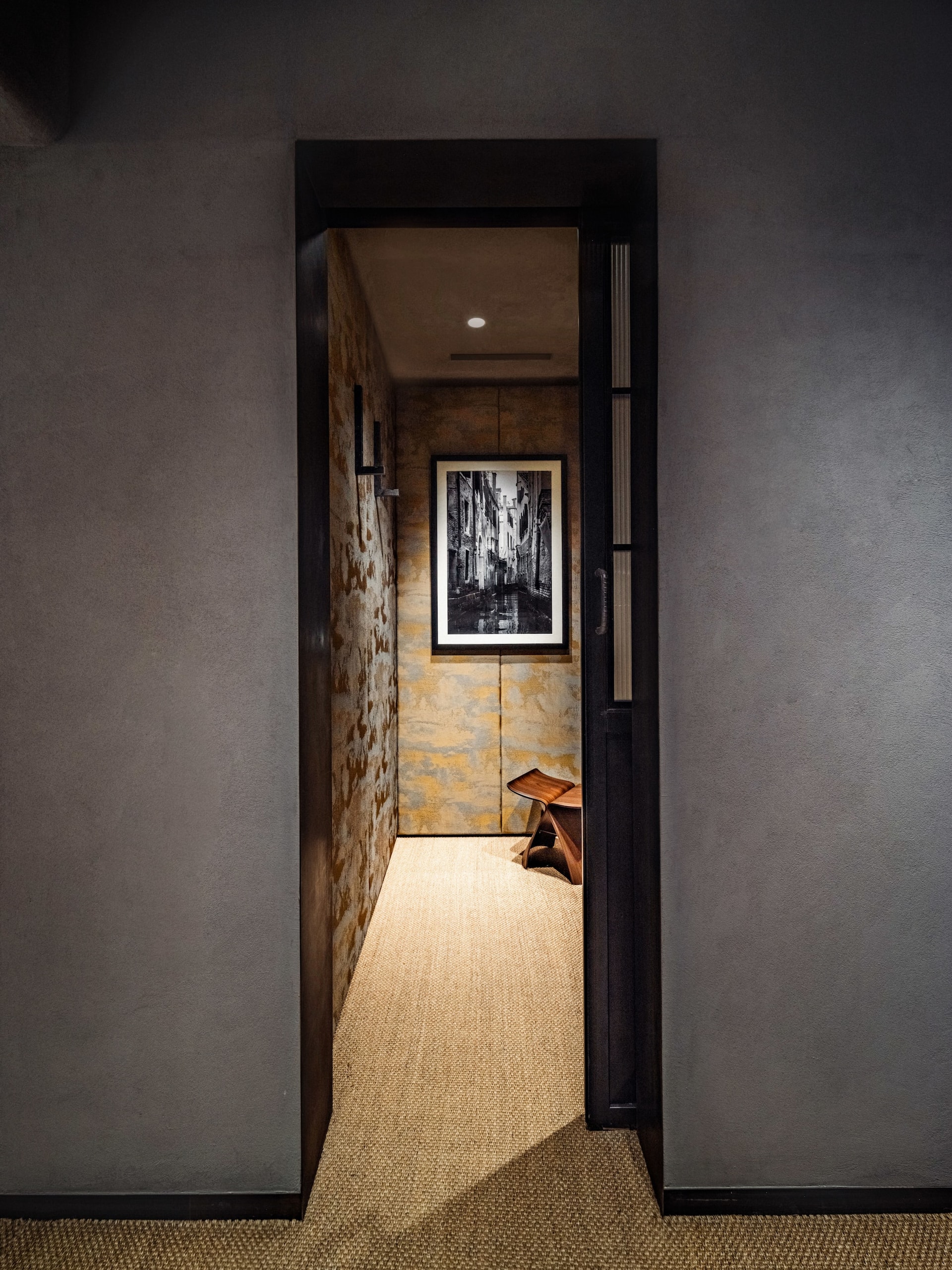 Dark narrow hallway leading to framed Venice photograph on textured wall at Tokyo Haus location