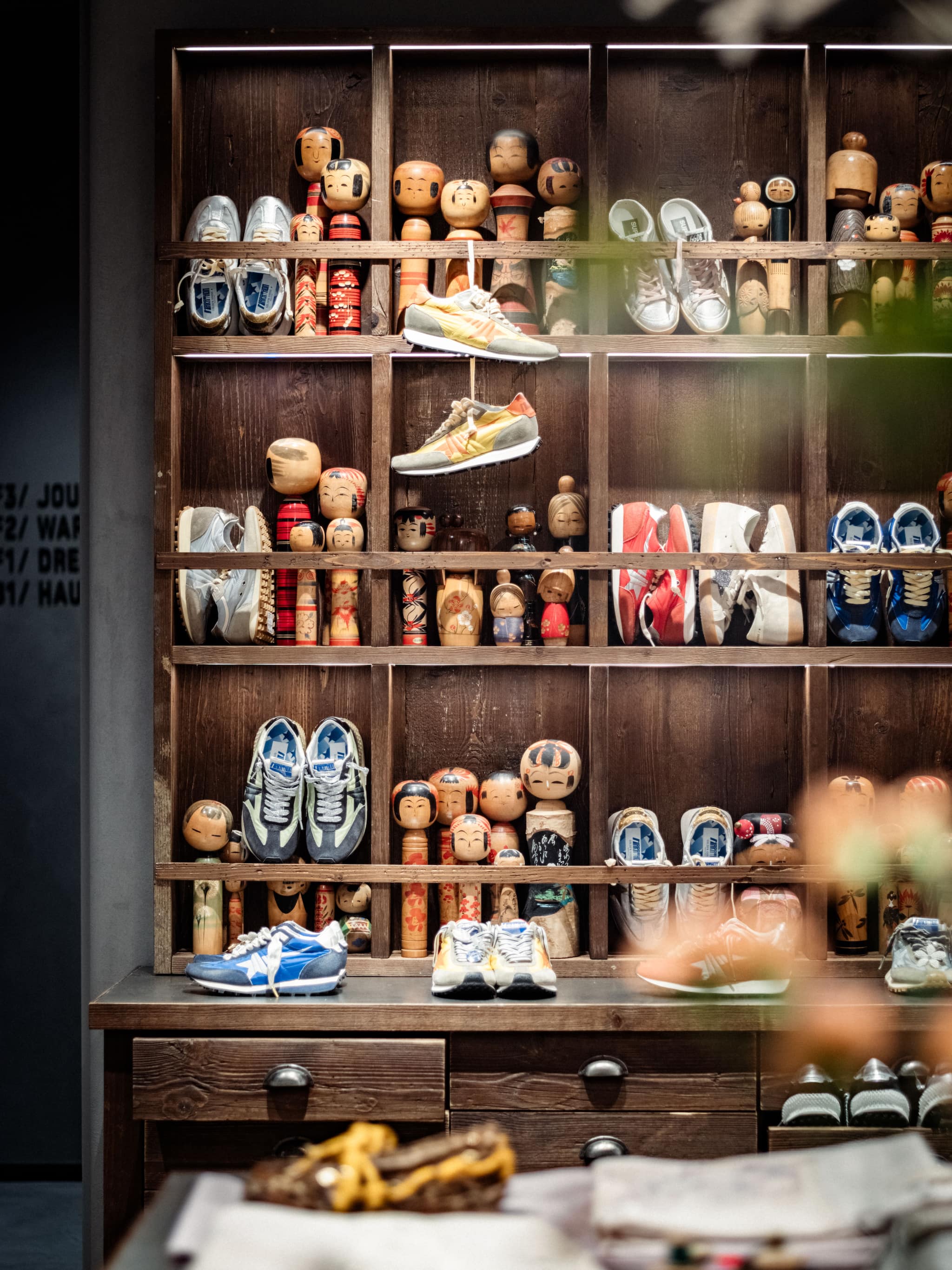 Wooden shelving unit displaying Kokeshi dolls and sneakers at Tokyo Haus location