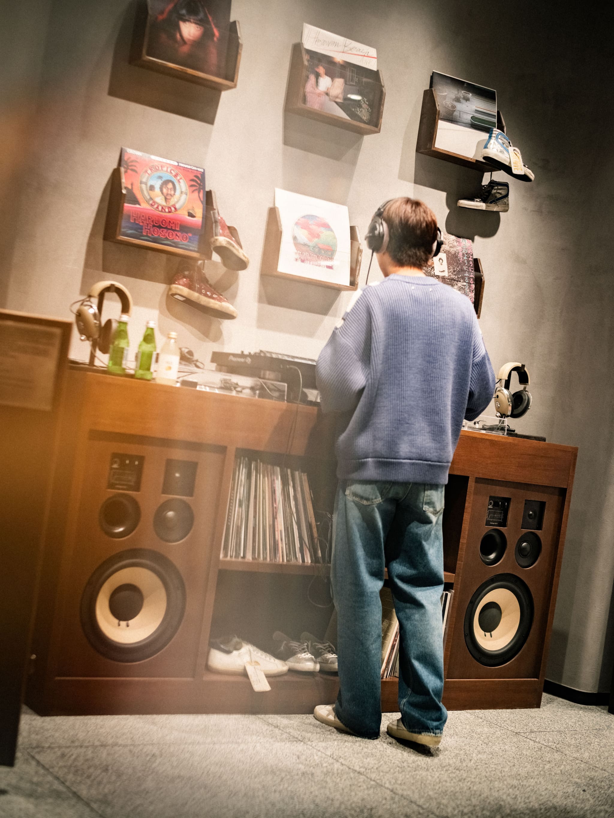 Man listening to headphones by vinyl record wall and DJ setup at Tokyo Haus event