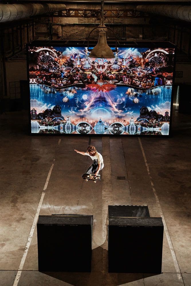Overhead view of skateboarder performing trick over ramp in front of screen at Haus event